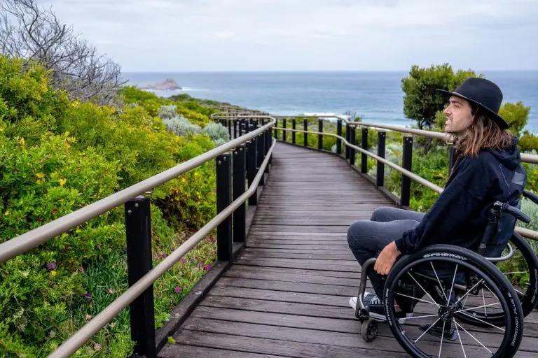 Man wearing hat in wheelchair takes a breather on the accessible wooden track on the Cape to Cape walk